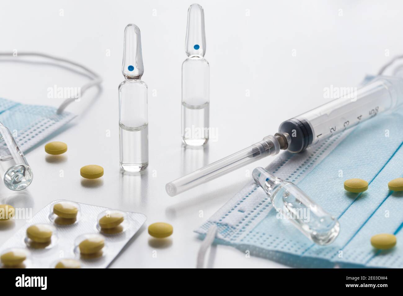 Medical face masks, pills, ampullas and expendable syringe for vaccination. Coronavirus vaccination concept. COVID-19 outbreak - Wuhan, China. Stock Photo