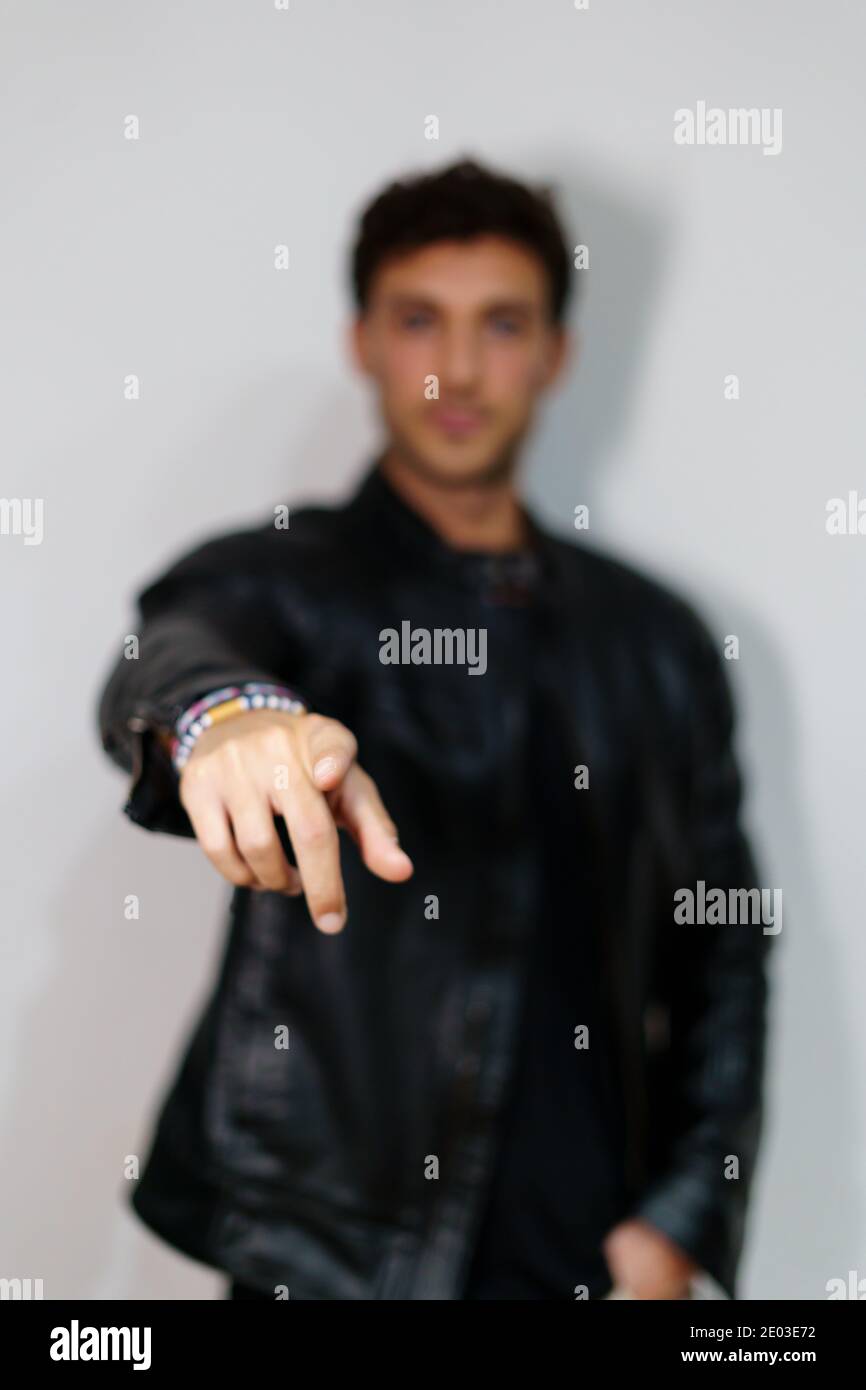 Vertical photo with selective focus on the hand of a man in informal clothes pointing to the front in a white background Stock Photo