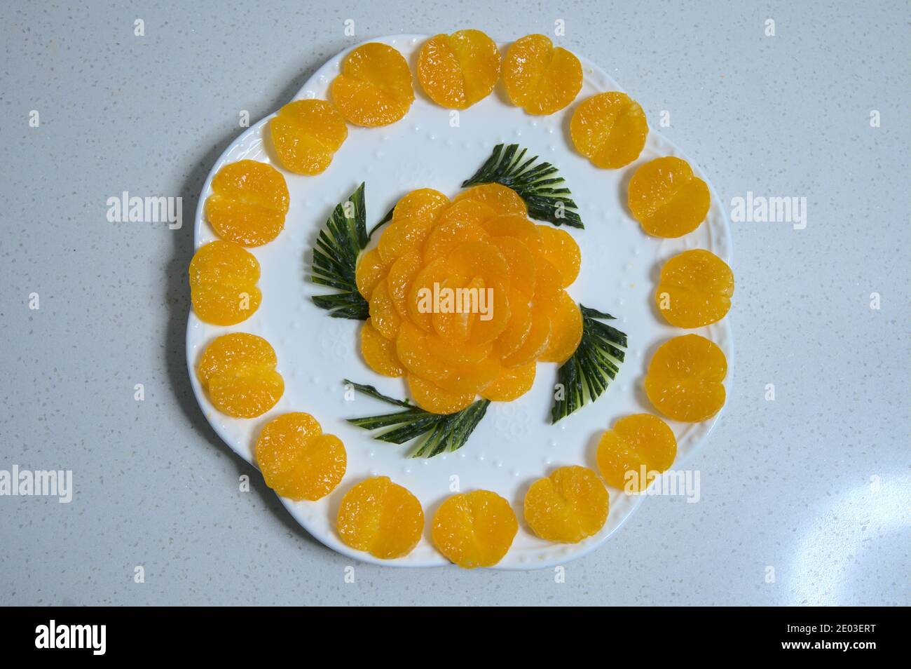Golden orange slices arranged in circle around plate, shape of flower in middle, top view Stock Photo