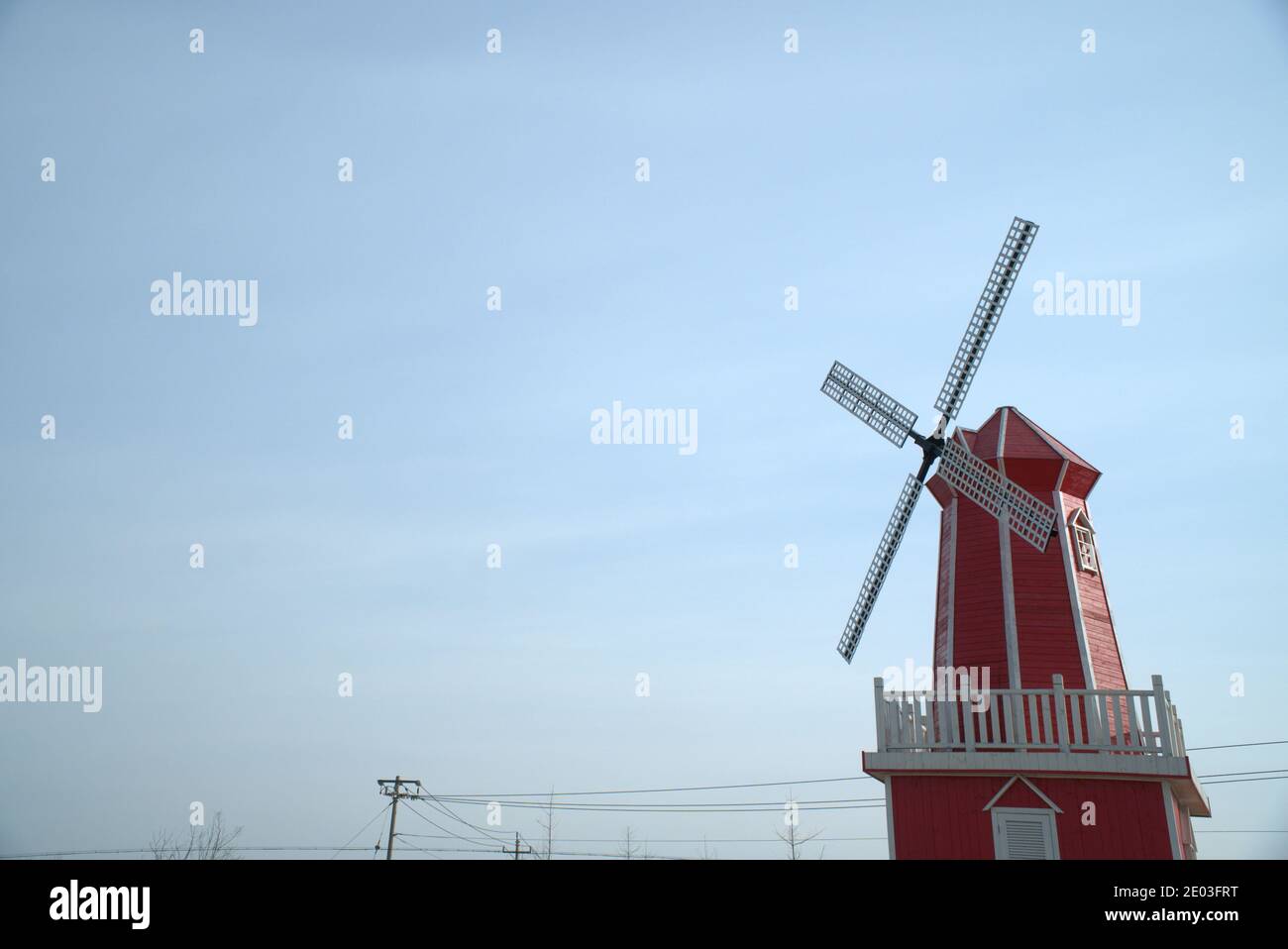 Traditional red wooden windmill, light blue sky background, copy space