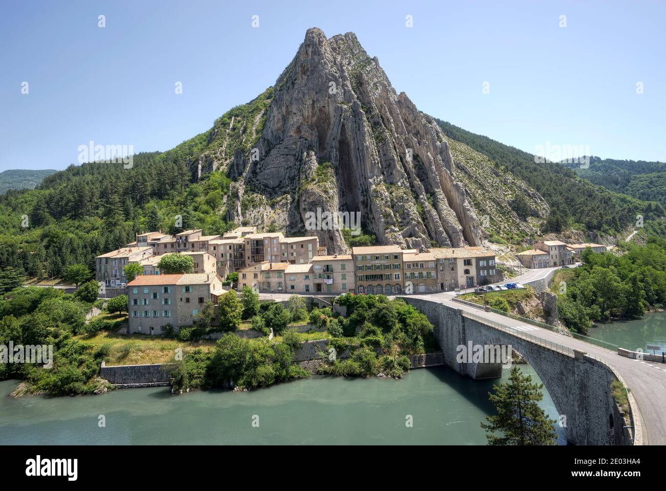 Small village next to Durance River and bridge at foot of cone shaped mountain in Sisteron Provence France in the foothills of the French Alps Stock Photo