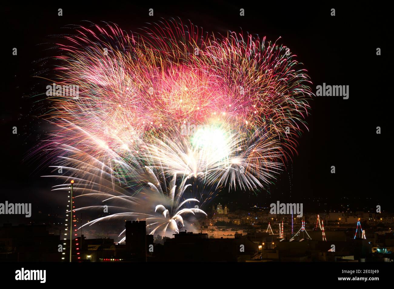 Fireworks. Colorful huge fireworks explode in dark sky background and house light in the far in Zurrieq, Malta Malta fireworks festival, 4 of July, In Stock Photo