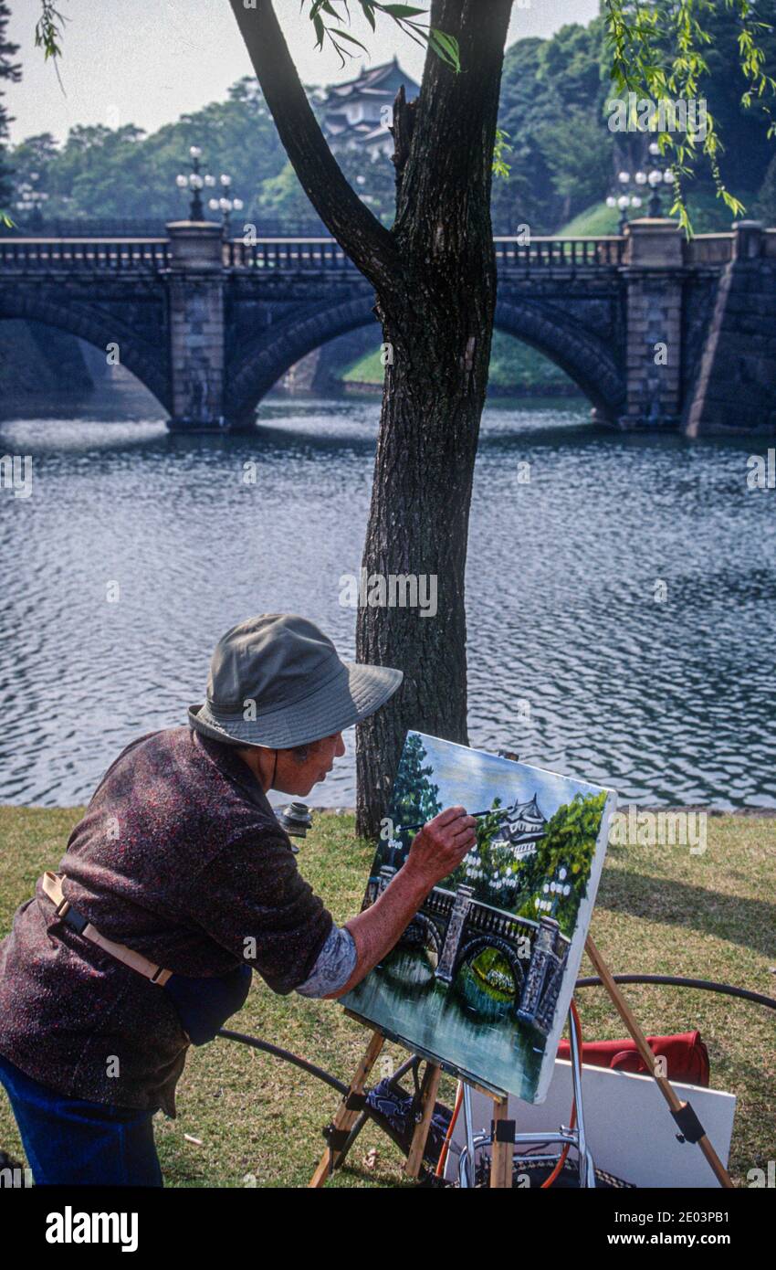 Japanese artist at work pianting the Seimon Ishibashi bridge, which forms the main entrance over the moat, to the Imperial Palace, Tokyo, Japan, May 1998 Stock Photo
