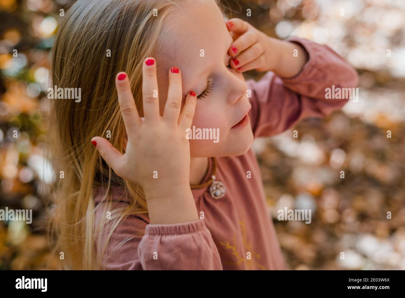 Female short blonde hair, red lipstick and red nail polish wearing black  dangly earrings and red velvet dress thin straps Stock Photo - Alamy