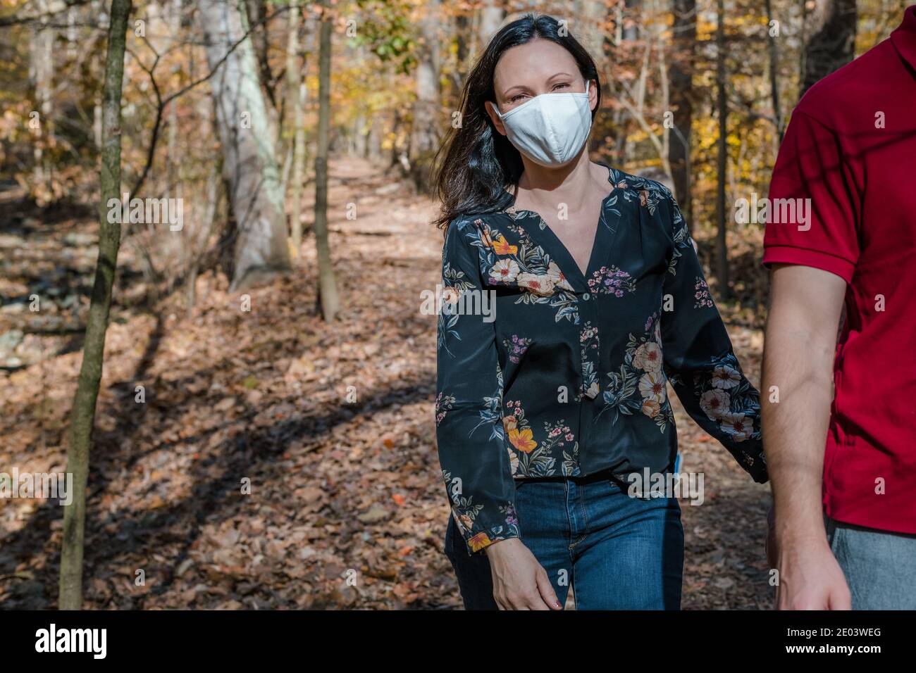 Middle age woman wearing face mask on hike in woods Stock Photo