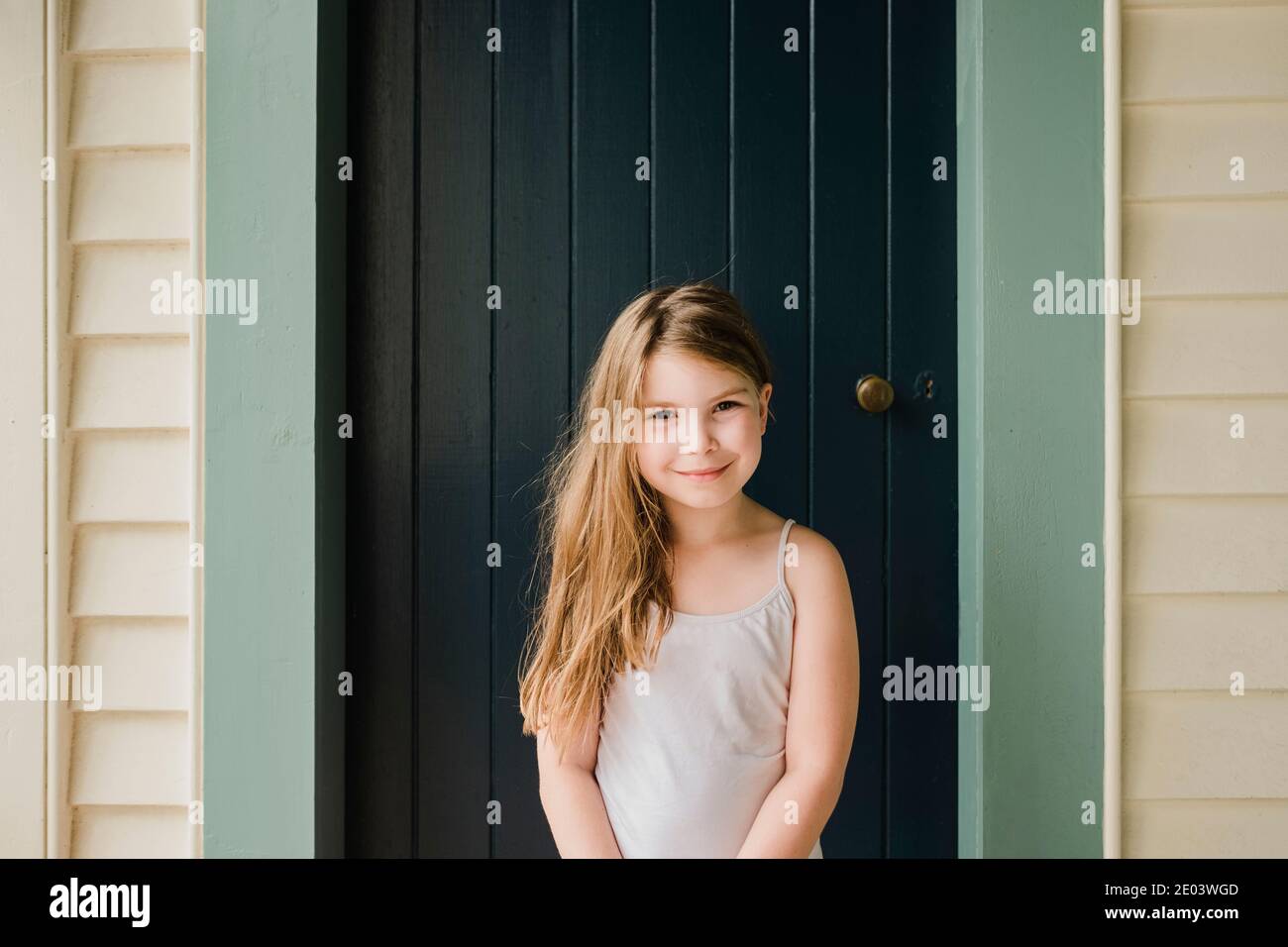 Smiling young girl standing outside in front of a door Stock Photo - Alamy