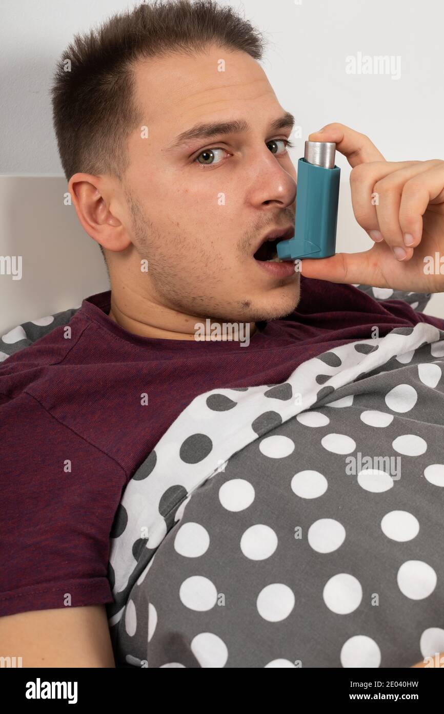 Young male patient with seasonal influenza is using an inhaler with ...