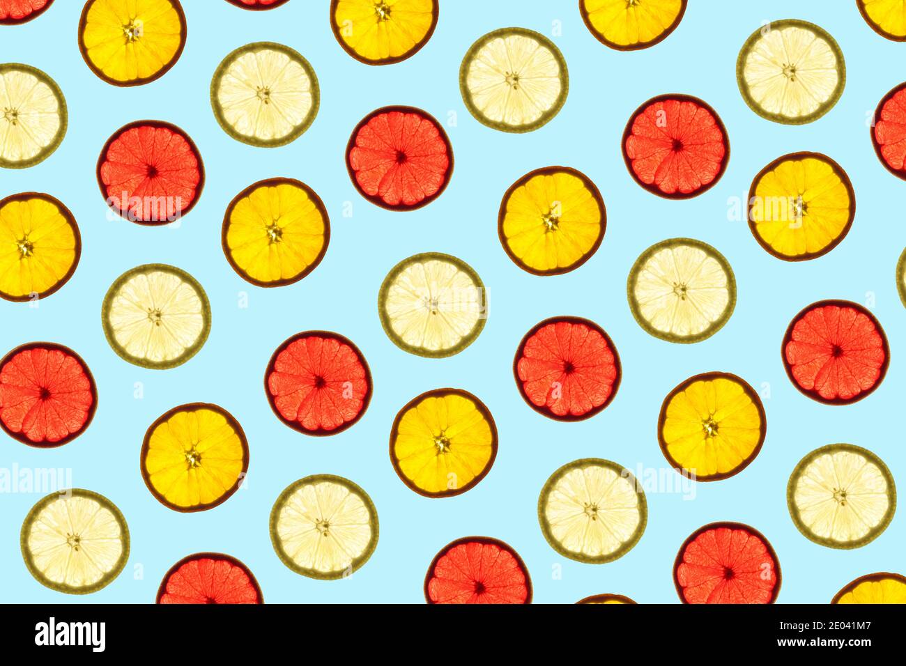Pattern made of backlit citrus fruits slices on blue background Stock Photo