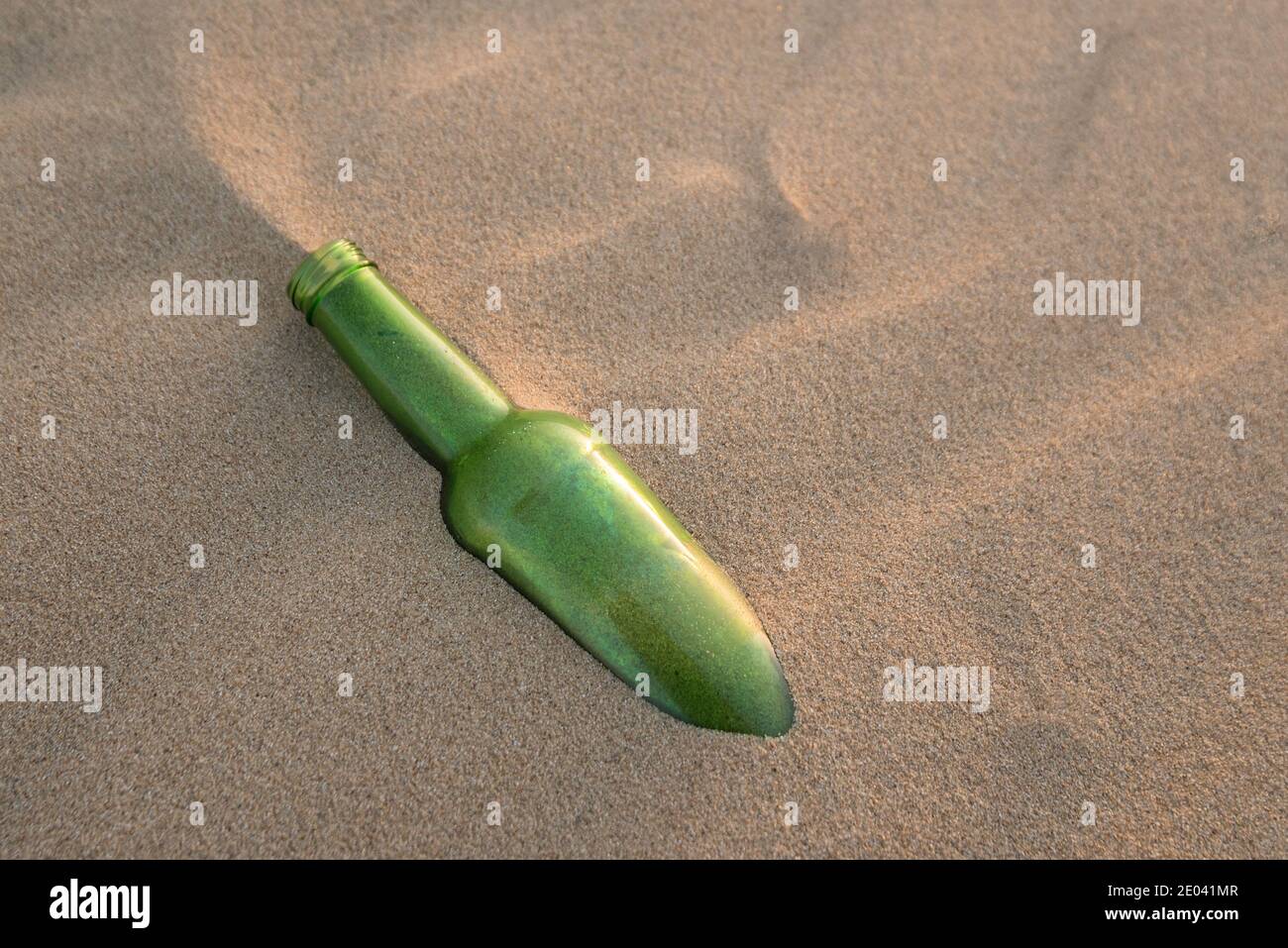 A bottle half buried in the sand Stock Photo