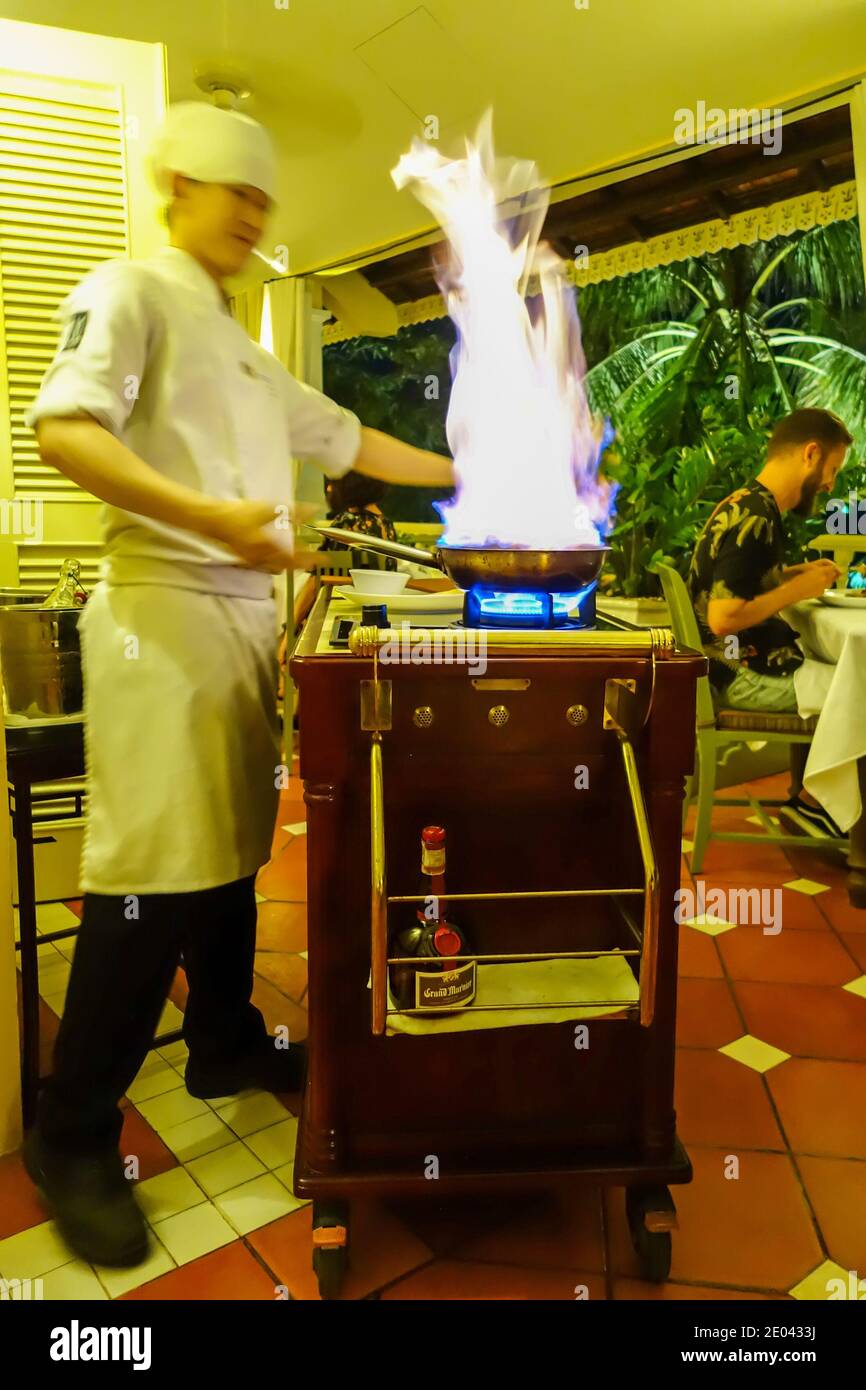 A chef cooking crepes suzette on a portable stove at the table in the restaurant at La Veranda luxury resort hotel, Phu Quoc island, Vietnam, Asia Stock Photo