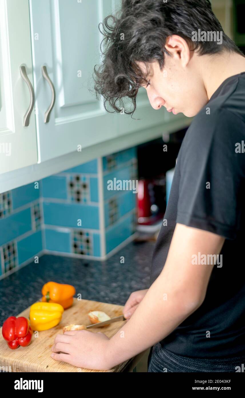 Mixed race teenage boy prepares vegetables in kitchen Stock Photo