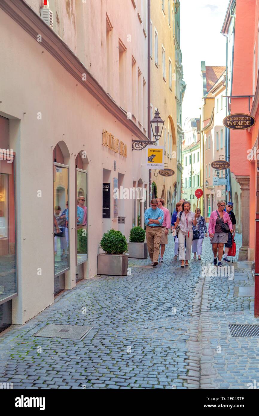 Intense building colors cast a rainbow on tourists in Regensburg's Old Town, Bavaria, Germany. Stock Photo