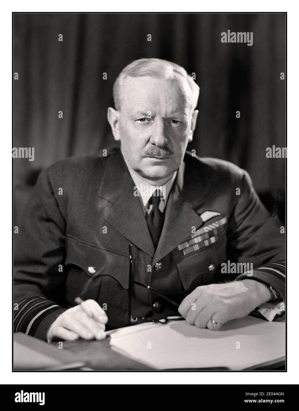 BOMBER HARRIS ARCHIVE Portrait Air Chief Marshal Sir Arthur Harris, Commander in Chief of Royal Air Force Bomber Command,  nicknamed ‘Bomber Harris” seated at his desk, smoking a cigarette at Bomber Command HQ. A controversial figure whose bombing tactics responded  to Nazi Luftwaffe Blitz terror bombing in the UK. Bomber Harris took the fight directly back to Adolf Hitler in Nazi Germany with huge success.  High Wycombe. 24 April 1944 Stock Photo