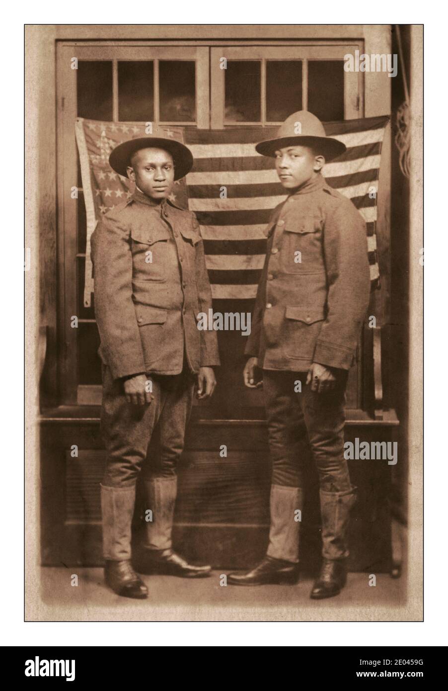 WW1 Propaganda Photo showing the contribution black African Americans gave to the First World War .Two unidentified African American soldiers in uniforms and campaign hats standing in front of American flag WW1 1918 [between 1917 and 1918]. United States.--Army--People--1910-1920 World War, 1914-1918--Military personnel--American African Americans--Military service--1910-1920 -  Soldiers--American--1910-1920 Military uniforms--American--1910-1920 Flags--American--1910-1920 Group portraits--1910-1920. Photographic postcards--1910-1920. Photographic prints--1910-1920. Portraits Stock Photo