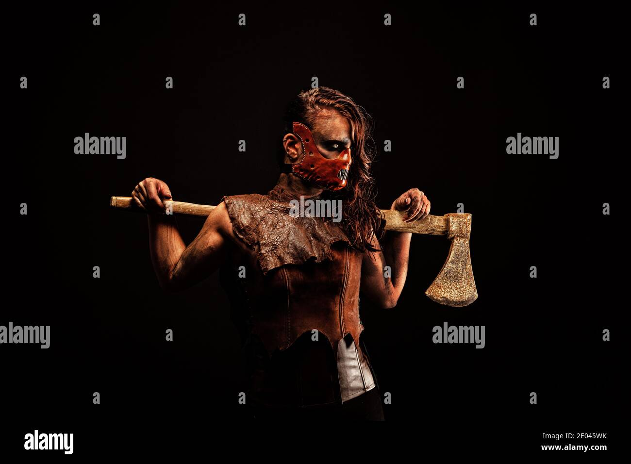 Murderous savage wearing a leather mask, armed with an ax that she carries on her shoulders Stock Photo