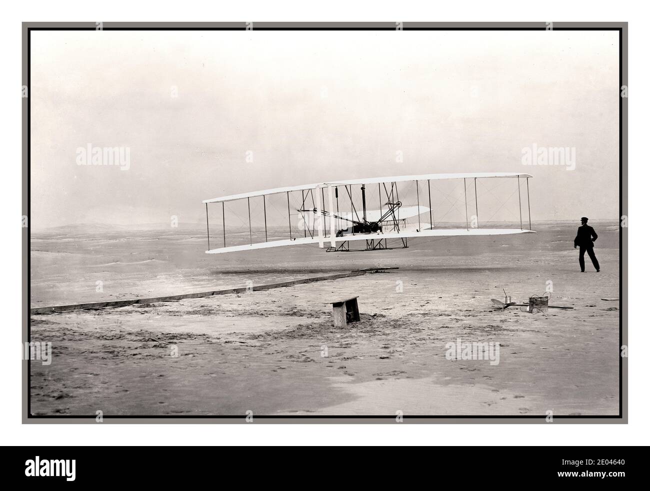 WRIGHT BROTHERS Archive FIRST POWERED FLIGHT Wright Brothers make first powered flight 1903 Kitty Hawk, North Carolina, USA America Photograph shows the first powered, controlled, sustained flight. Orville Wright at the controls of the machine, lying prone on the lower wing with hips in the cradle which operated the wing-warping mechanism. Wilbur Wright running alongside to balance the machine, has just released his hold on the forward upright of the right wing. The starting rail, the wing-rest, a coil box, and other items needed for flight preparation are visible behind the machine. Stock Photo