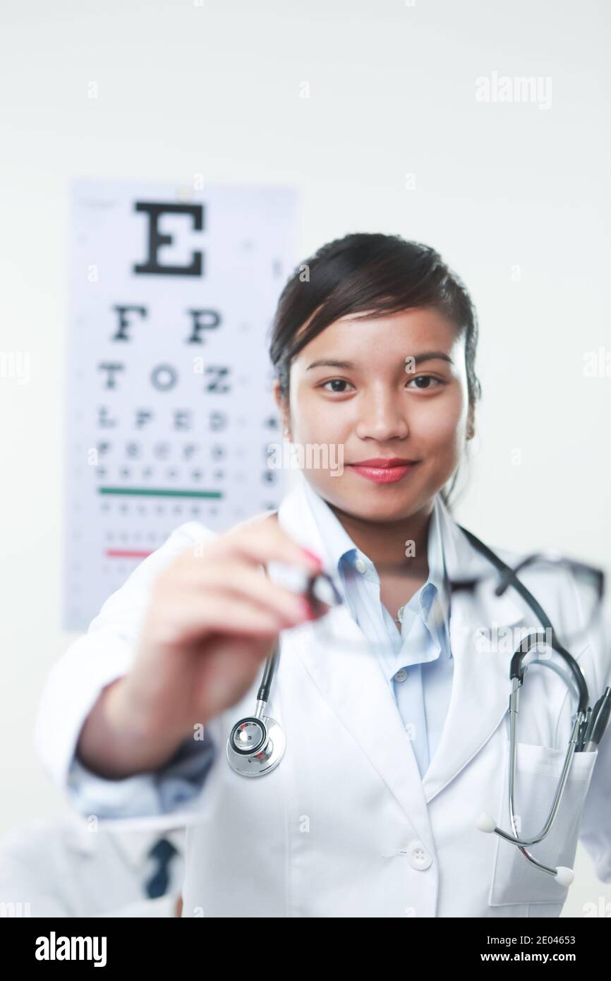 A female doctor with stethoscope and a vision chart at the back Stock Photo