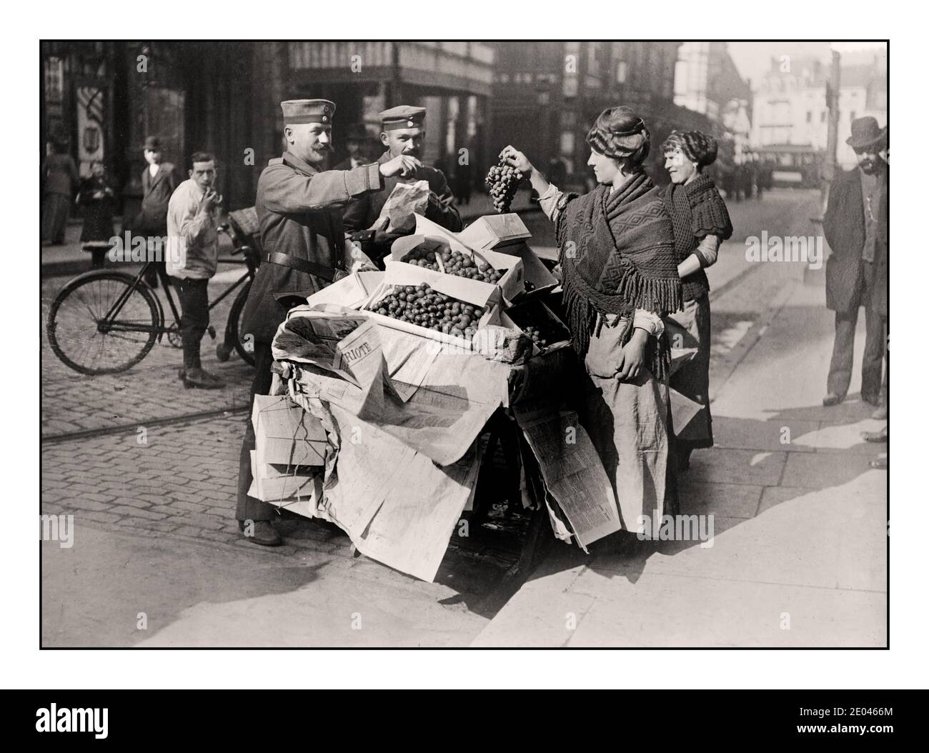 WW1 German Propaganda image of German soldiers buying apparently plentiful fruit /grapes -- on Belgian Street market stall in Belgium during World War 1 Photograph shows German soldiers purchasing grapes from women with a street cart in Belgium during World War I.  1915 April 13  World War 1, 1914-1918 Glass negatives.First World War Stock Photo