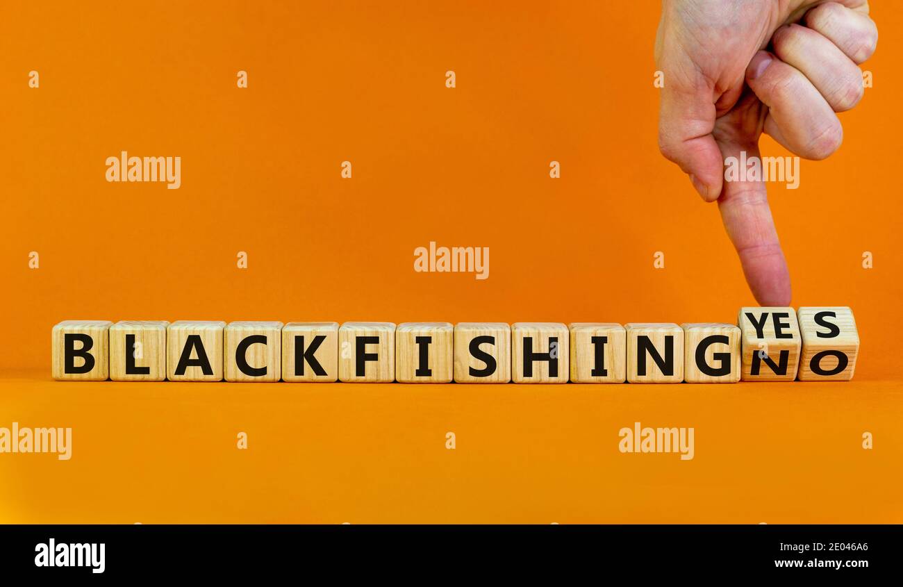 Blackfishing yes or no symbol. Male hand turns cubes and changes words 'Blackfishing no' to 'Blackfishing yes'. Beautiful orange background. Copy spac Stock Photo