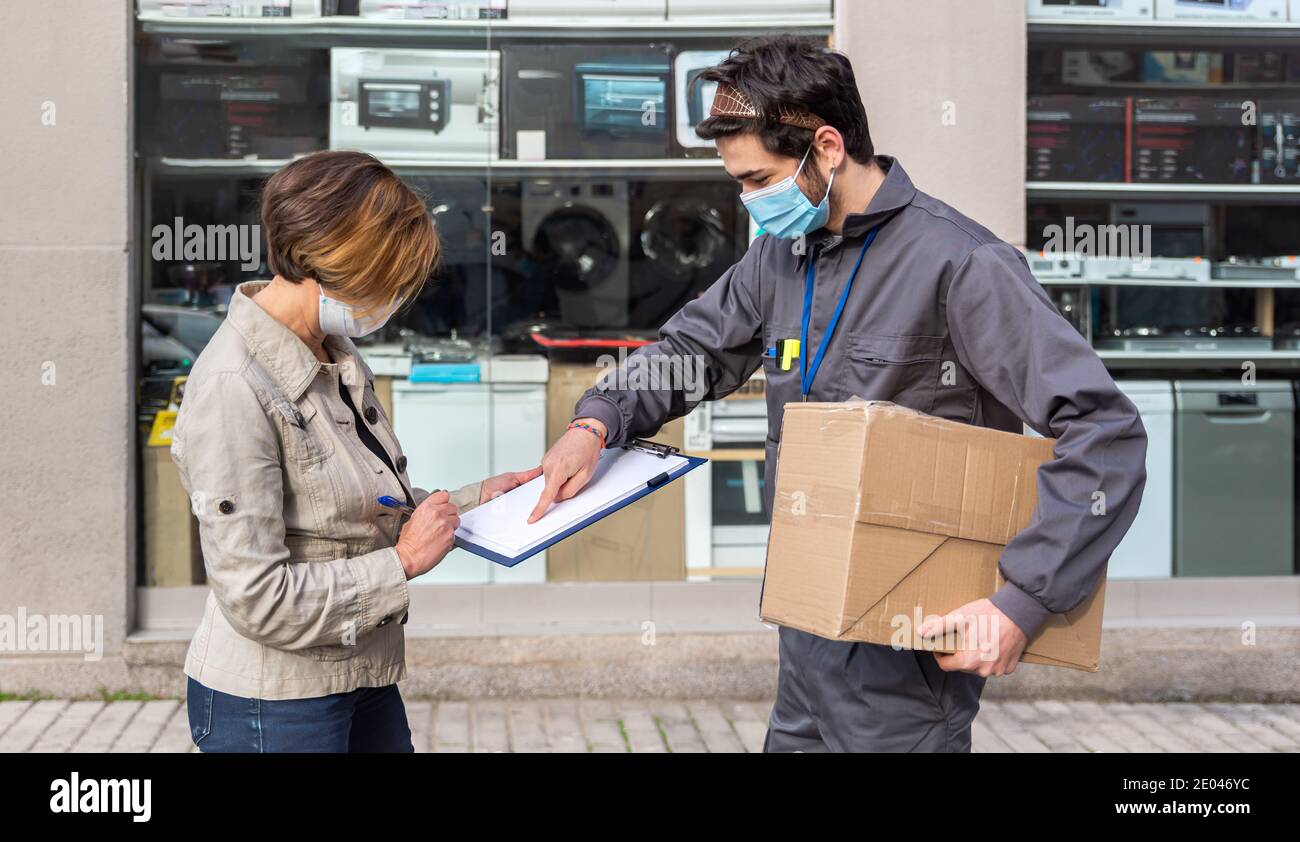 Delivery man wearing a face mask and a package delivered to the woman ...