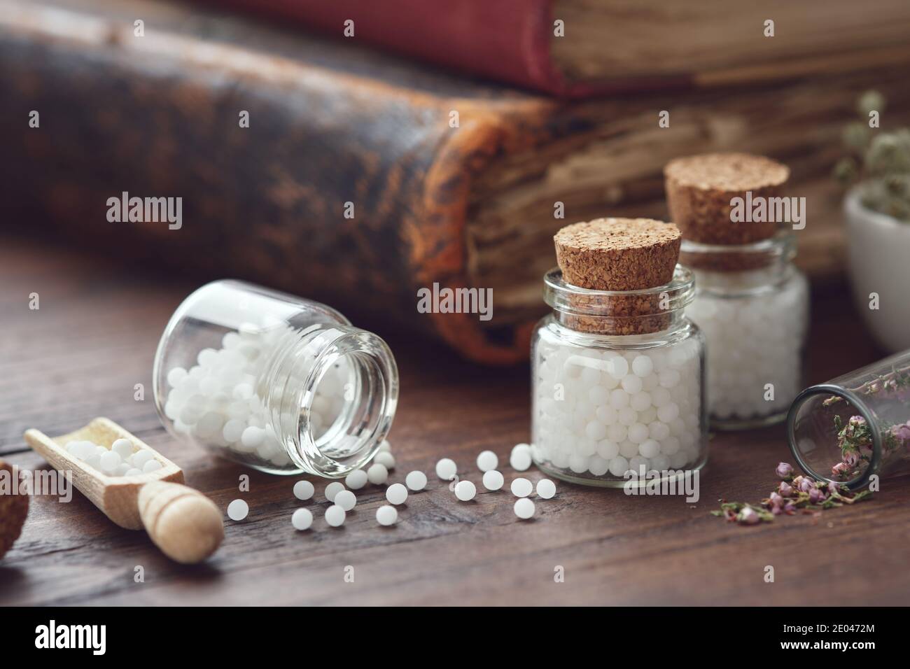 Bottles of homeopathic globules and old books. Homeopathy medicine concept. Stock Photo