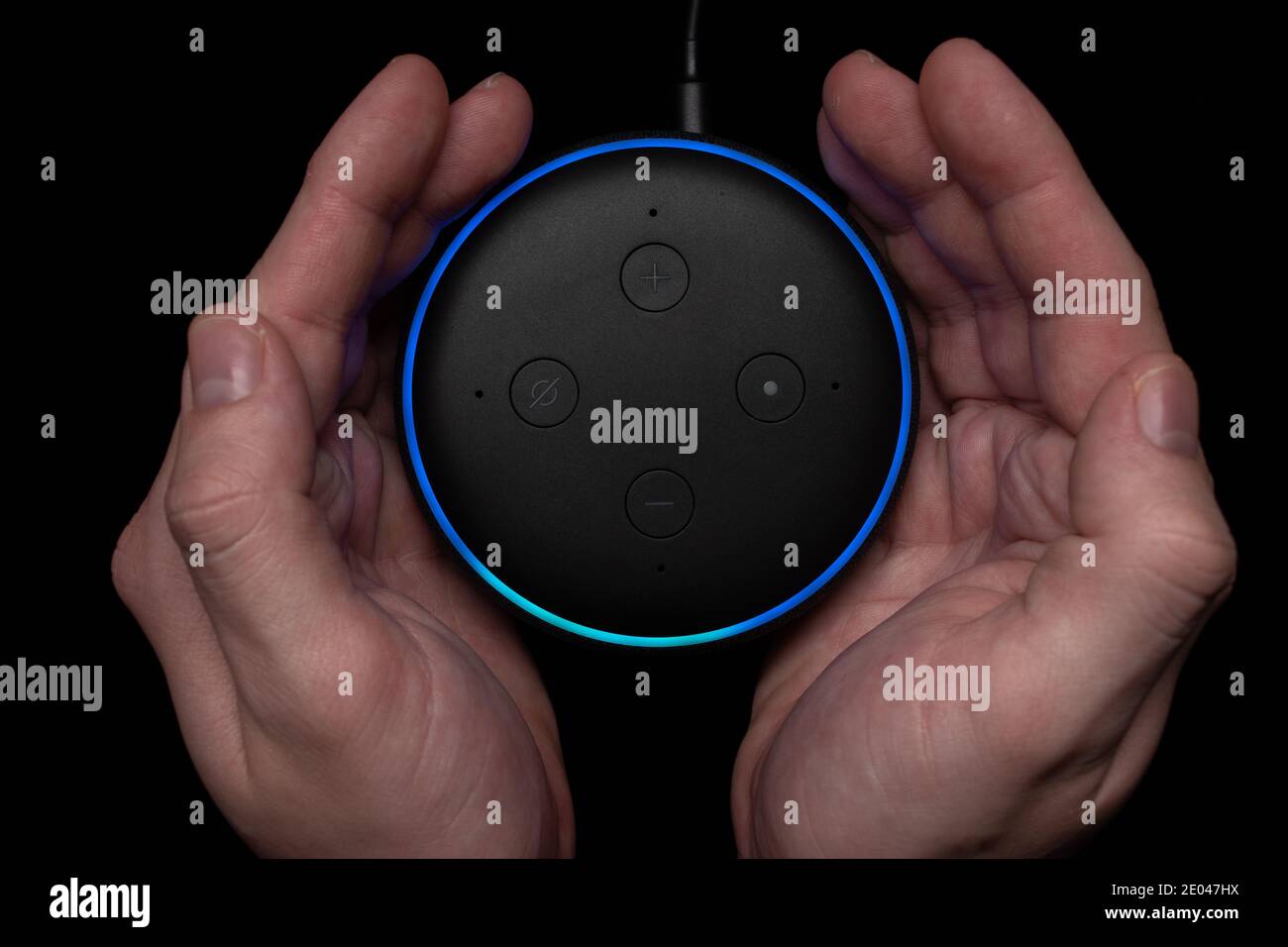 London, United Kingdom - December 19 2020: Hands around an Amazon Echo Dot smart speaker with built-in Alexa voice assistant. Stock Photo