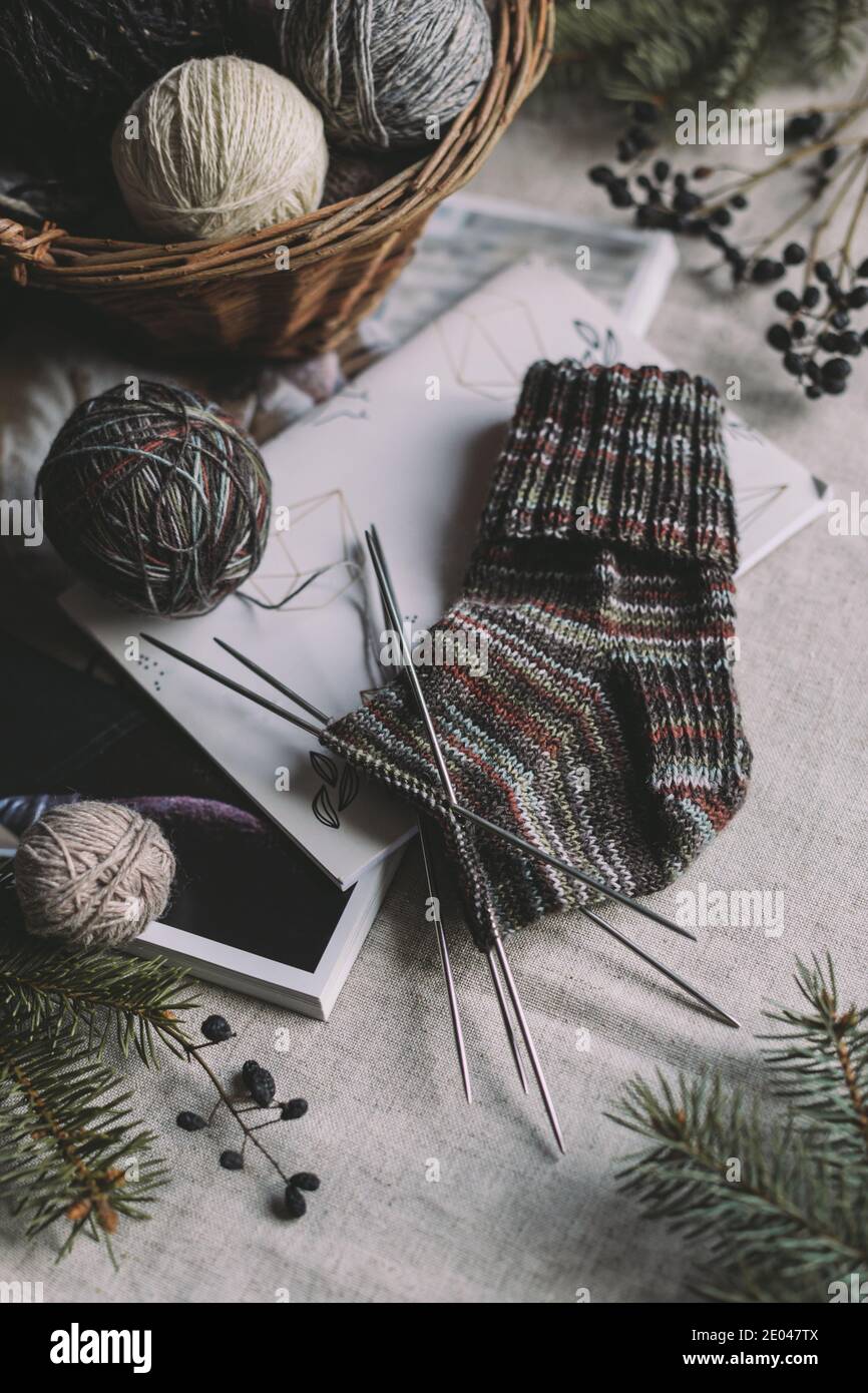Hand knitting sock with needles and yarn balls in a basket. Concept for handmade and hugge slow life. Stock Photo