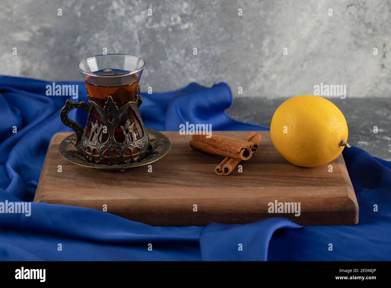 A glass tea with cinnamon sticks on a wooden cutting board Stock Photo