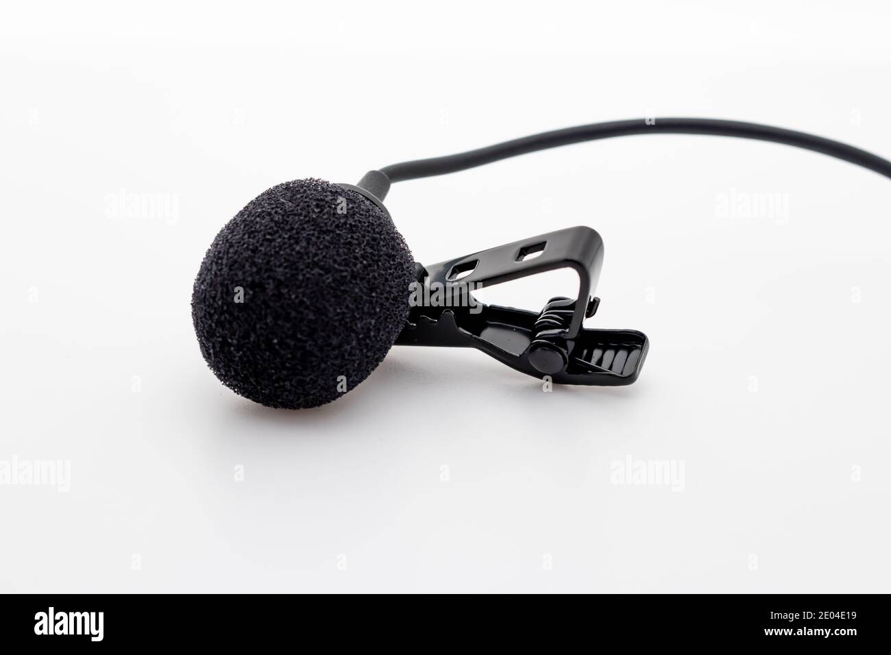 Lavalier or lapel microphone on a surface, very close-up. The details of the grip clip or bra and the sponge against the wind are visible. Stock Photo