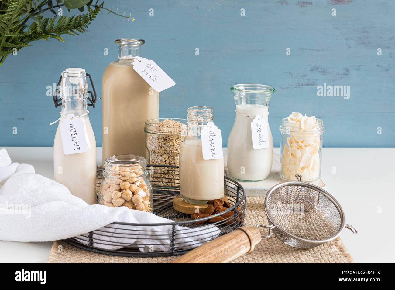 Bottles of alternative tagged milks in on a rustic tablecloth. Crystal jars full of seeds ,cereal and nuts are next to them. Stock Photo