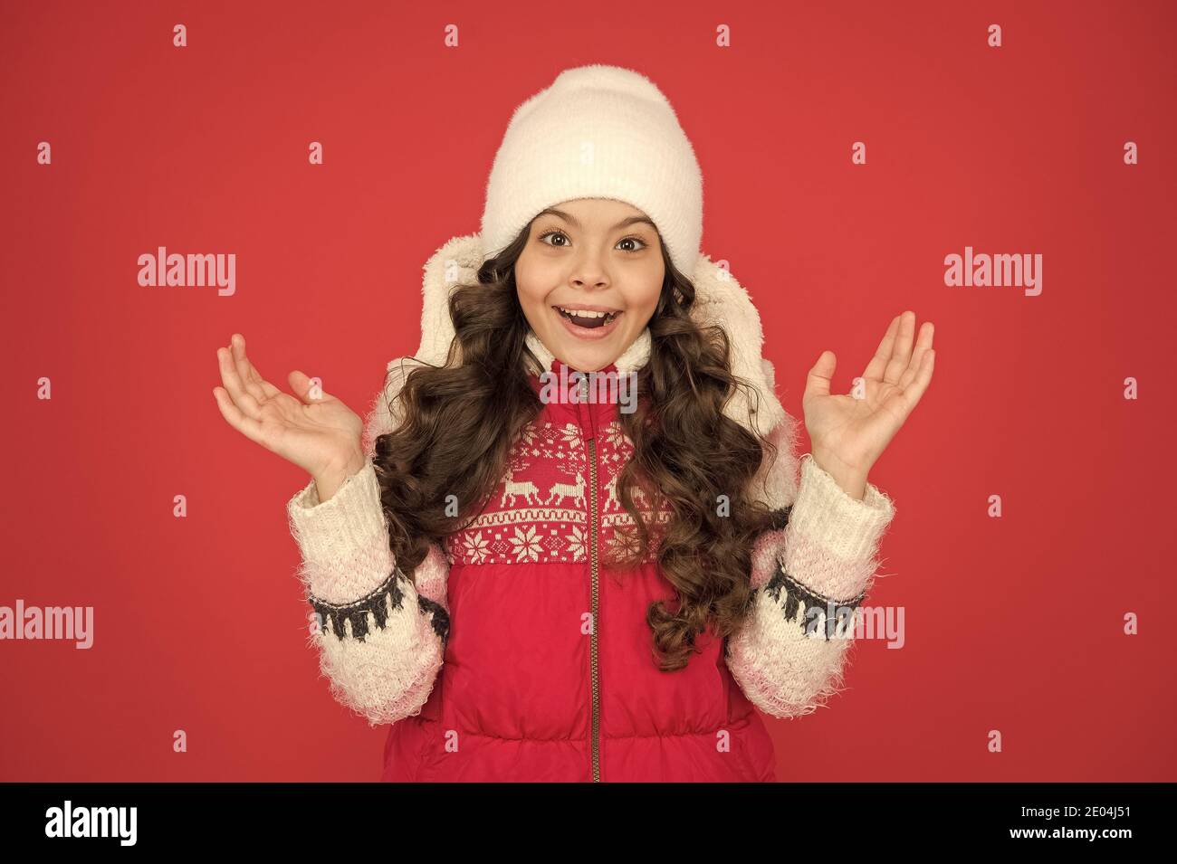 surprised about winter sales. portrait of pure beauty. small girl long  curly hair. its cold outside. winter outfit for kids. happy childhood.  child in knitted hat. feeling cosy in warm clothes Stock