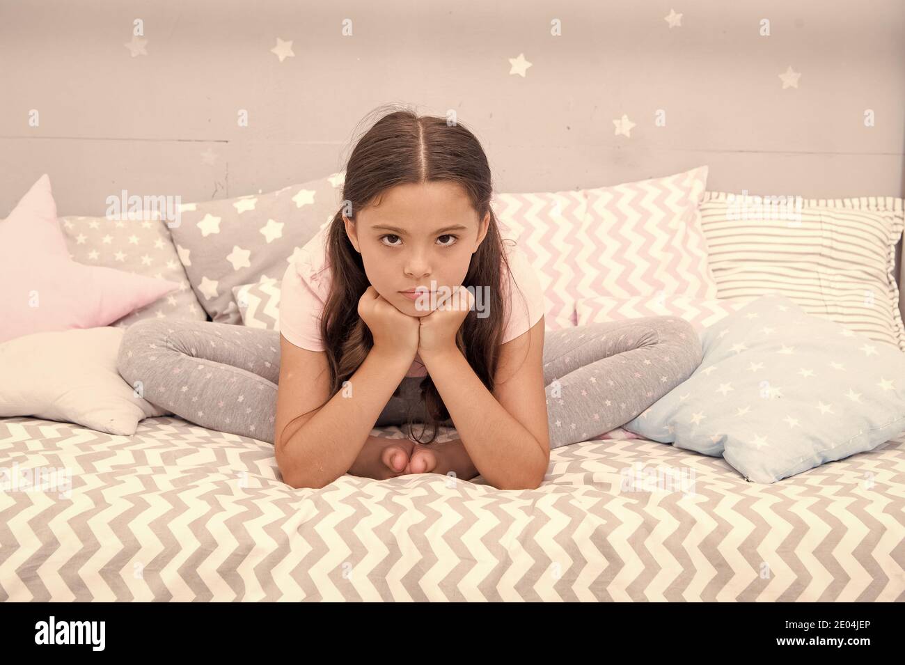 Why so sad. Sad girl sit in bed. Little child with sad look. Bedtime routine. Daytime nap. Kids health. Childcare. Early morning hour. Good night. Unhappy and sad. Stock Photo