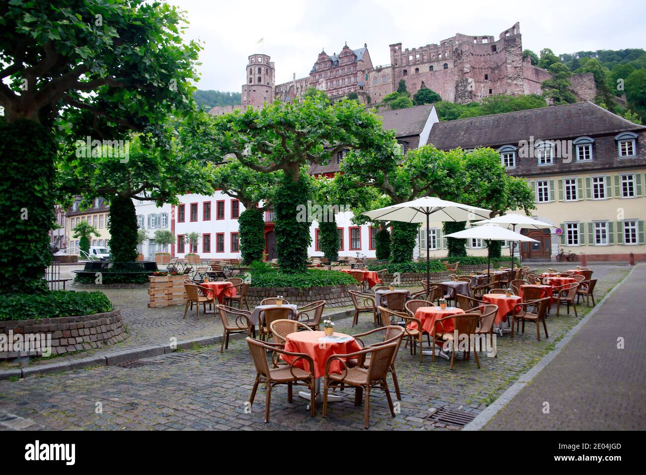 Karlsplatz mit der Akademie der Wissenschaften, dahinter das Heidelberger Schloss, Tische und Stühle eines Restaurants sind menschenleer durch Corona- Stock Photo