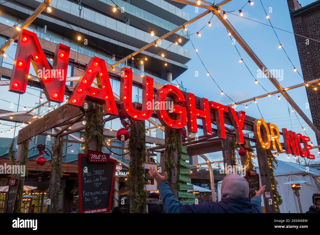 A red lit sign that reads Naughty or Nice at an outdoor bar at the Toronto distillery district Christmas market Stock Photo