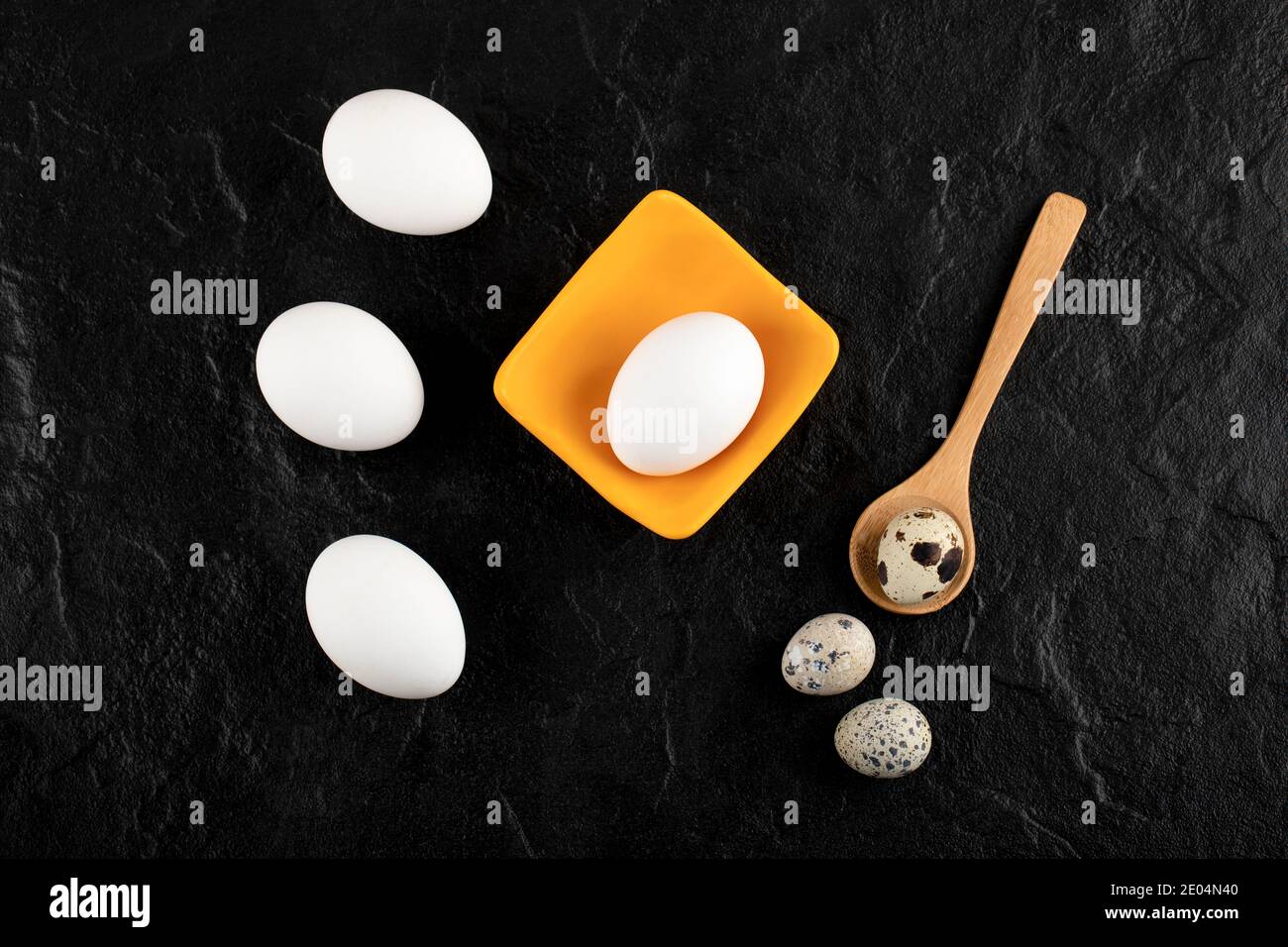 Quail eggs and chicken eggs on black background Stock Photo