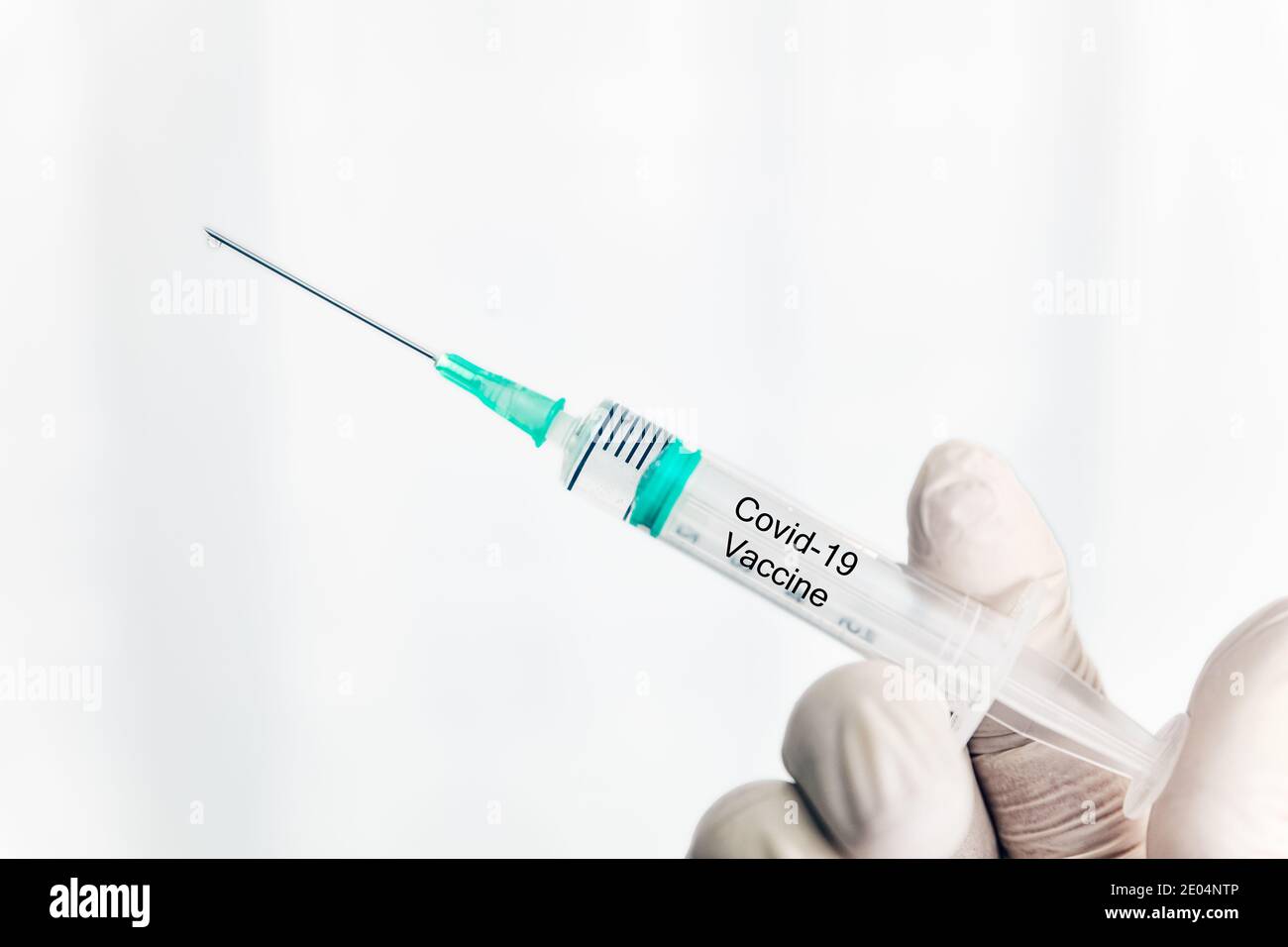 Male hand in white gloves holding a plastic syring with covid-19 vaccine, vaccination concept Stock Photo