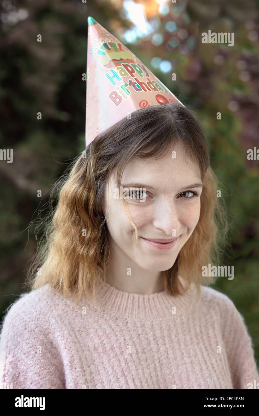 Portrait of a cute young woman wearing a birthday cone looking camera, outdoors Stock Photo
