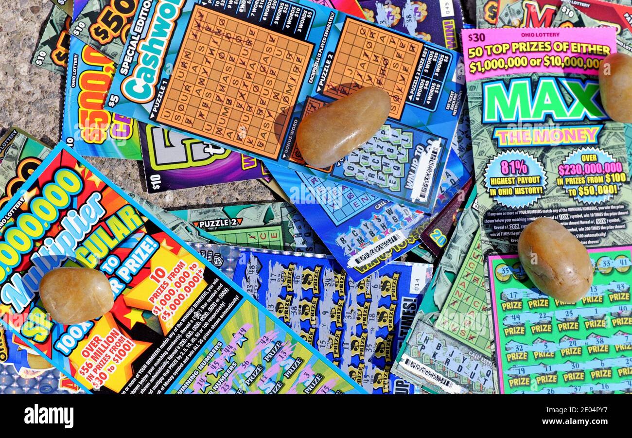 Varying types of scratch-off instant lottery tickets purchased in Ohio are held down by rocks. Stock Photo