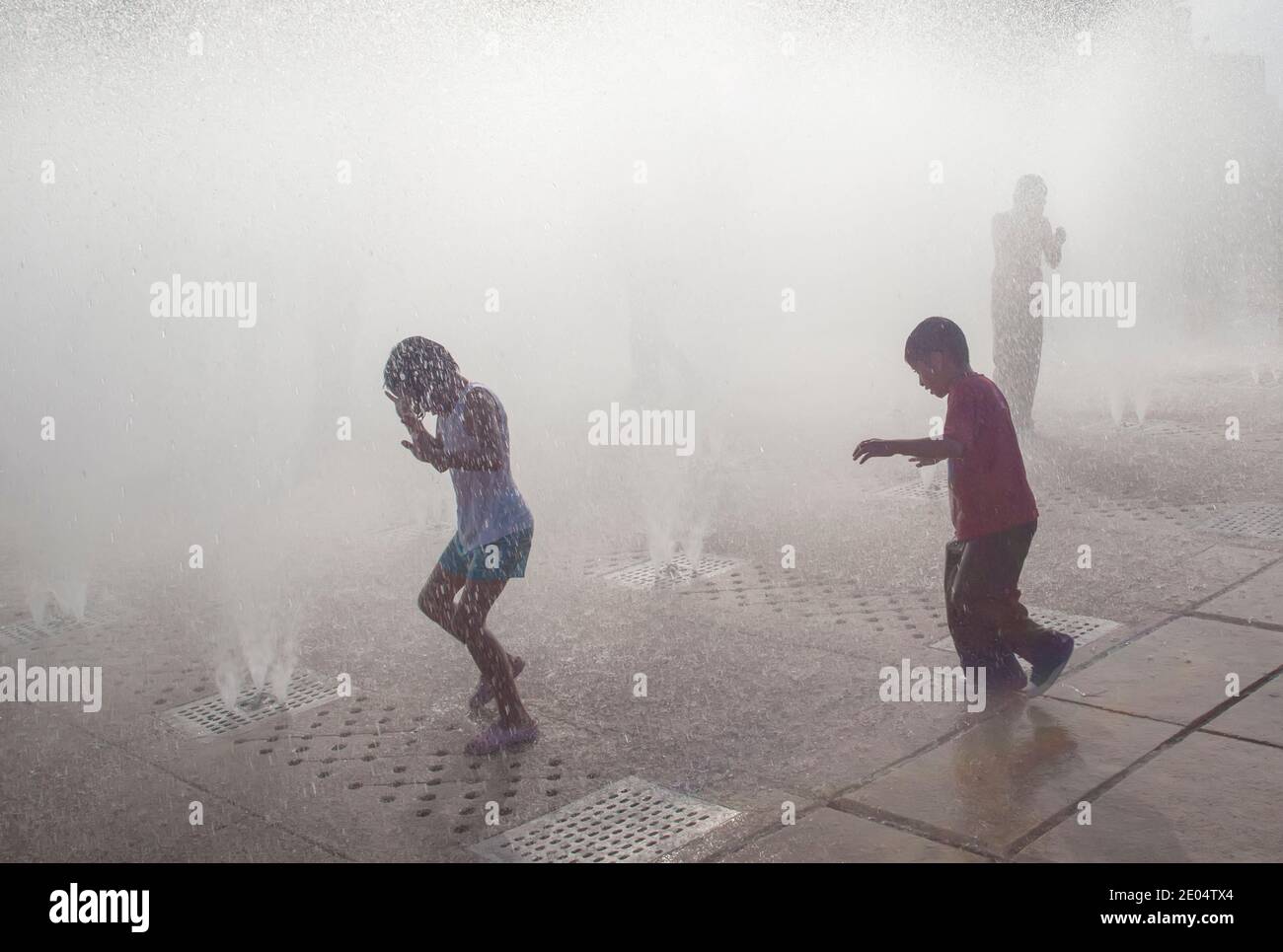 Children play in water fountains in Mexico City, Mexico during hot weather Stock Photo