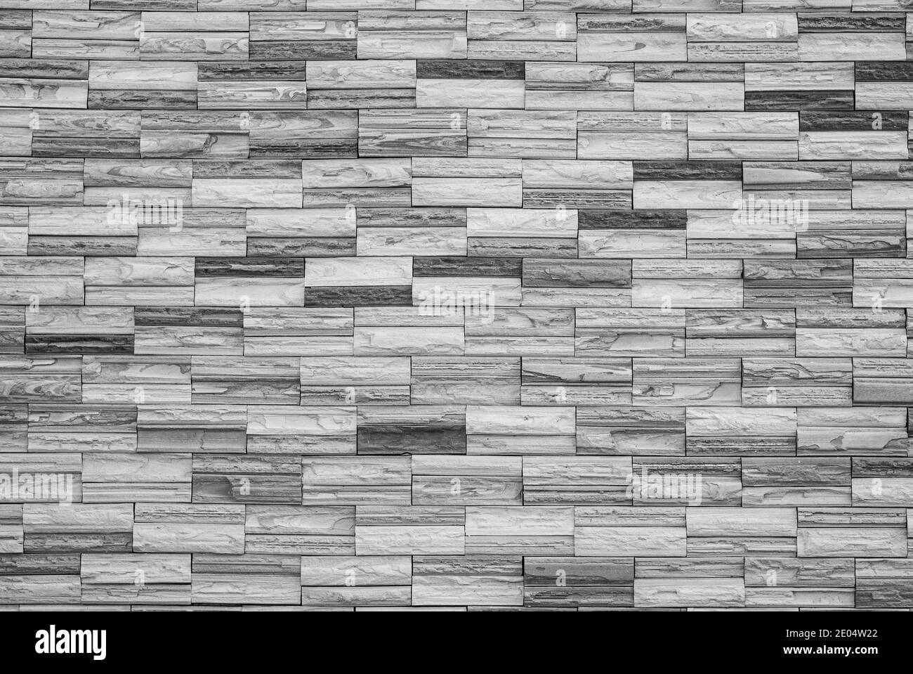 Natural craft stone tile wall made to random pattern background, black and white. Stock Photo