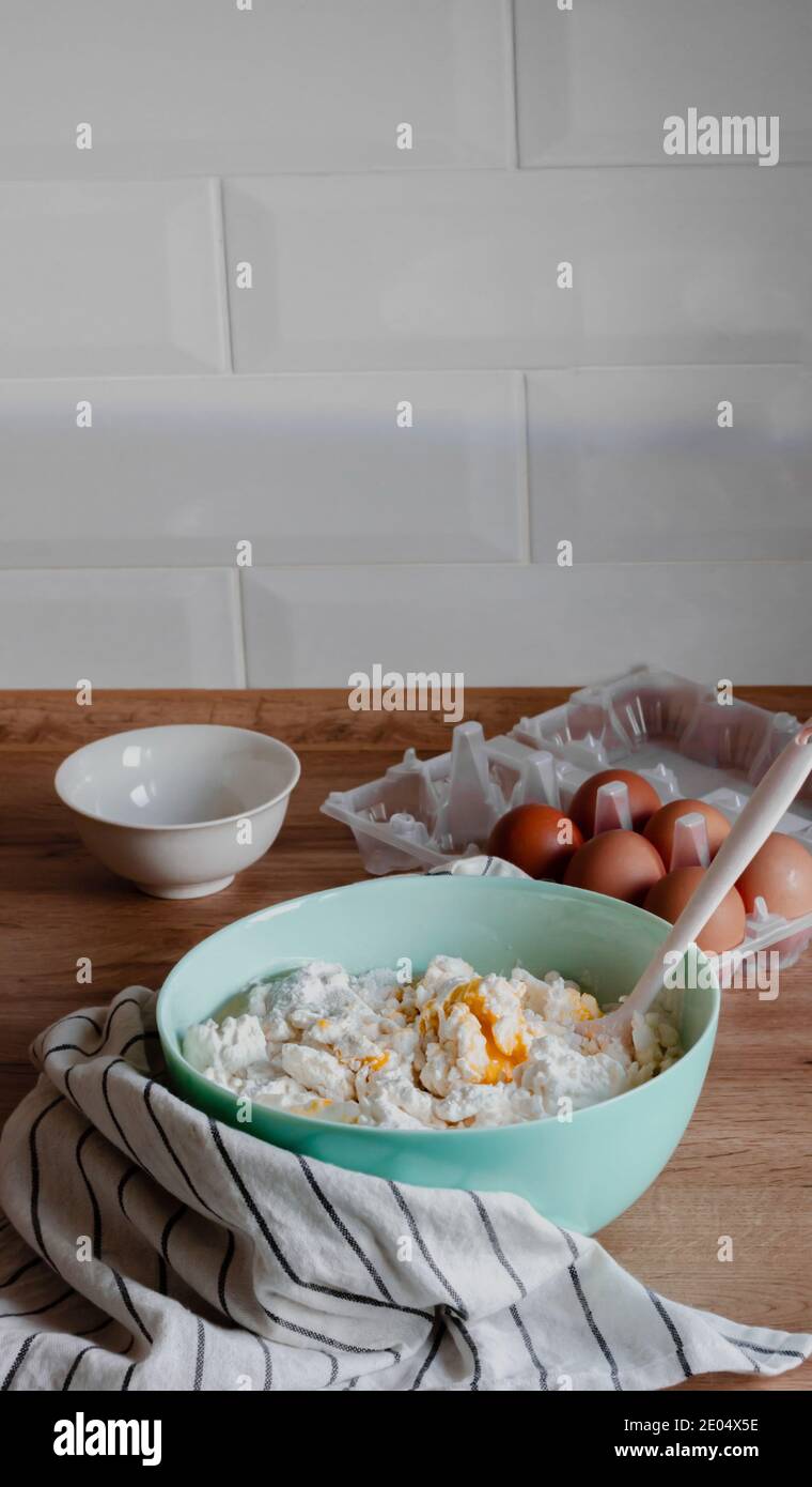 Cooking at home process illustrating pancakes pastry preparation in the modern wooden kitchen. Organic farm eggs, flour and cottage cheese ingredients Stock Photo