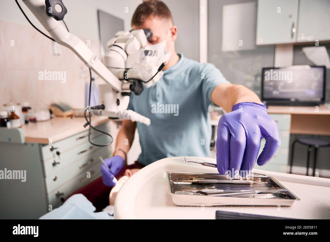 Close up of male dentist hand in sterile glove holding metal dental