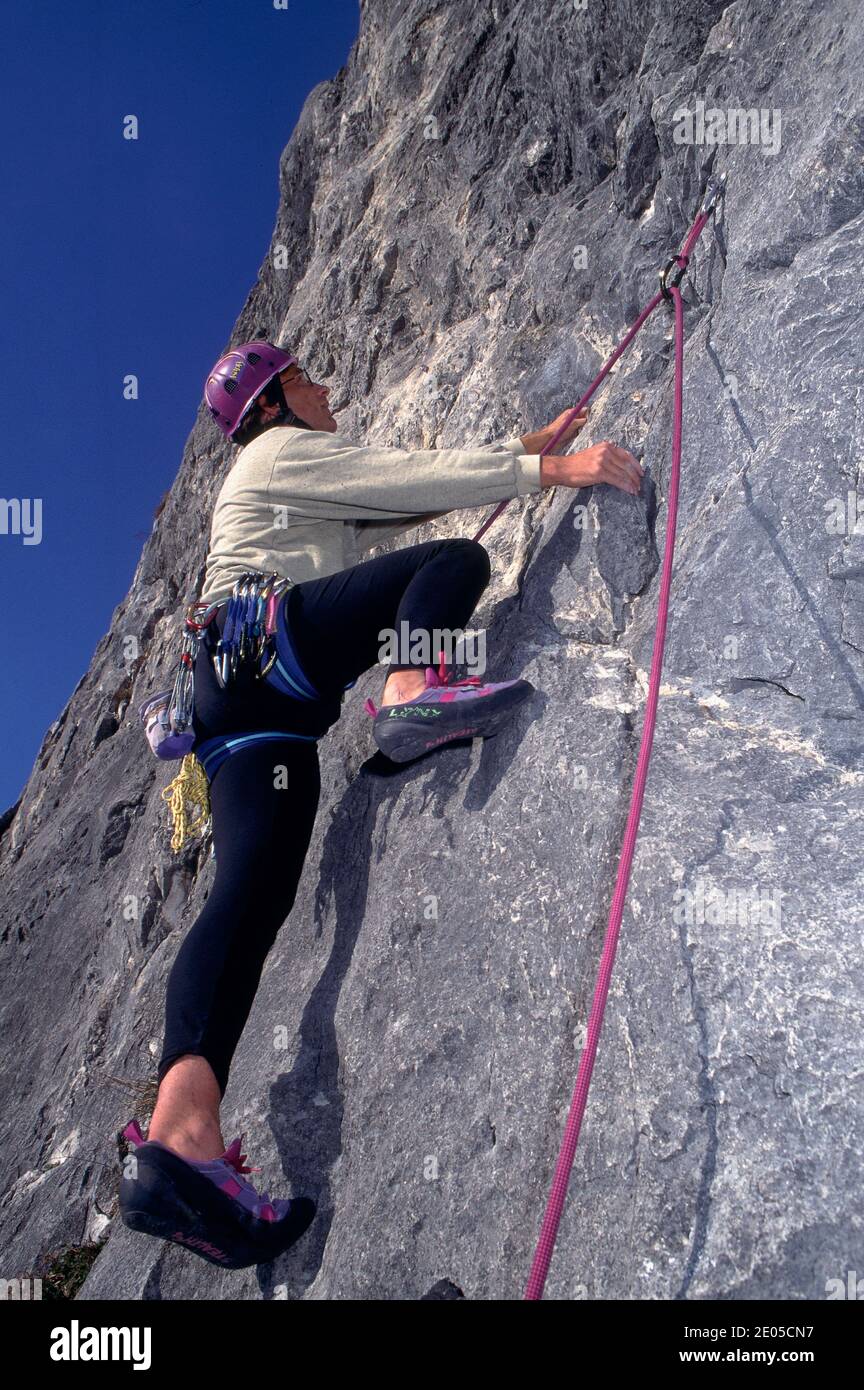 Caucasian male climber climbing a steep wall. In background a summer
