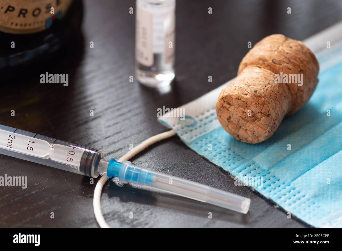 Syringe, vial, surgical face mask, bottle and cork. New year concept during Covid19 or Coronavirus emergency, no party Stock Photo