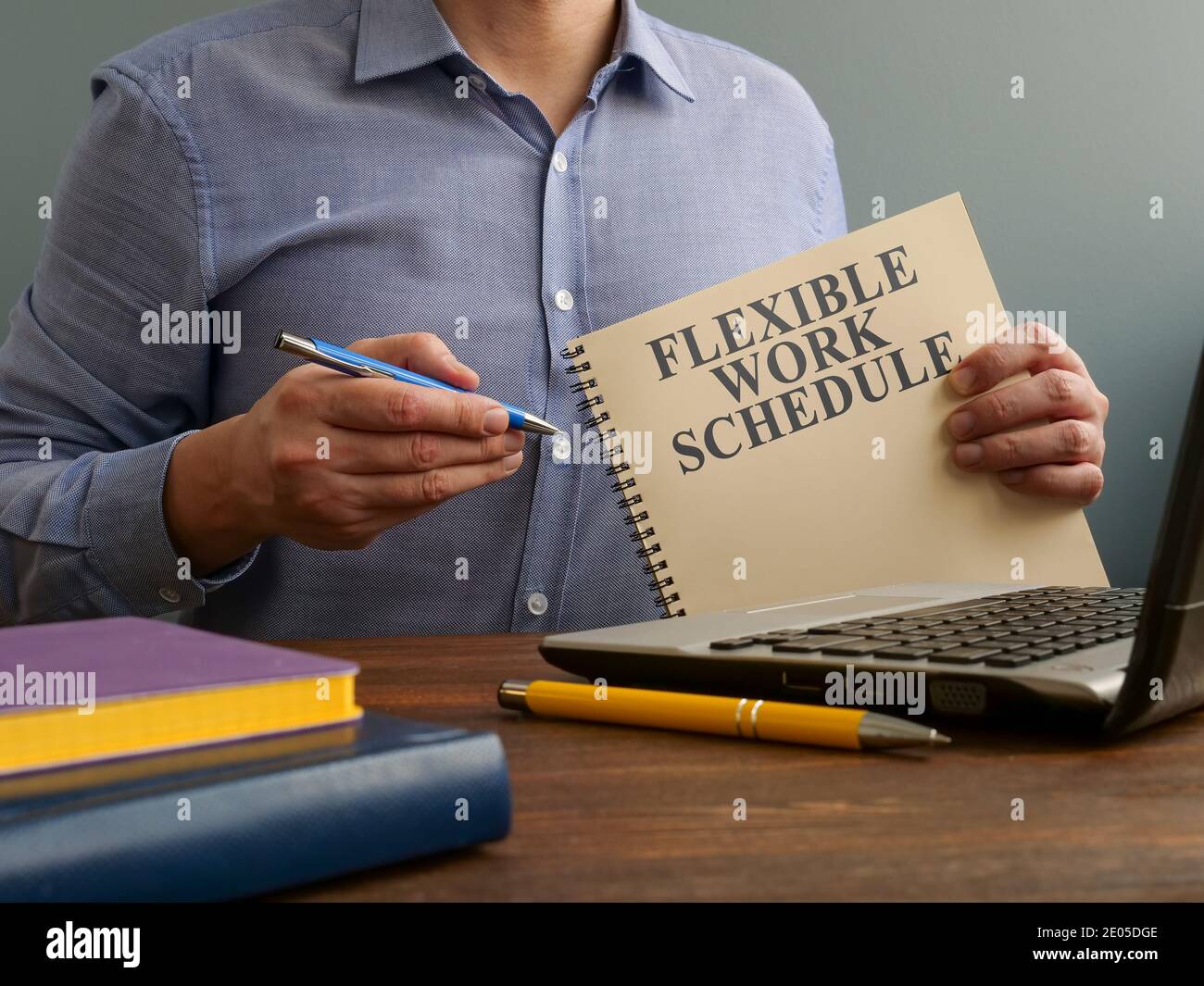 Man shows Flexible work schedule and offers a pen for filling. Stock Photo