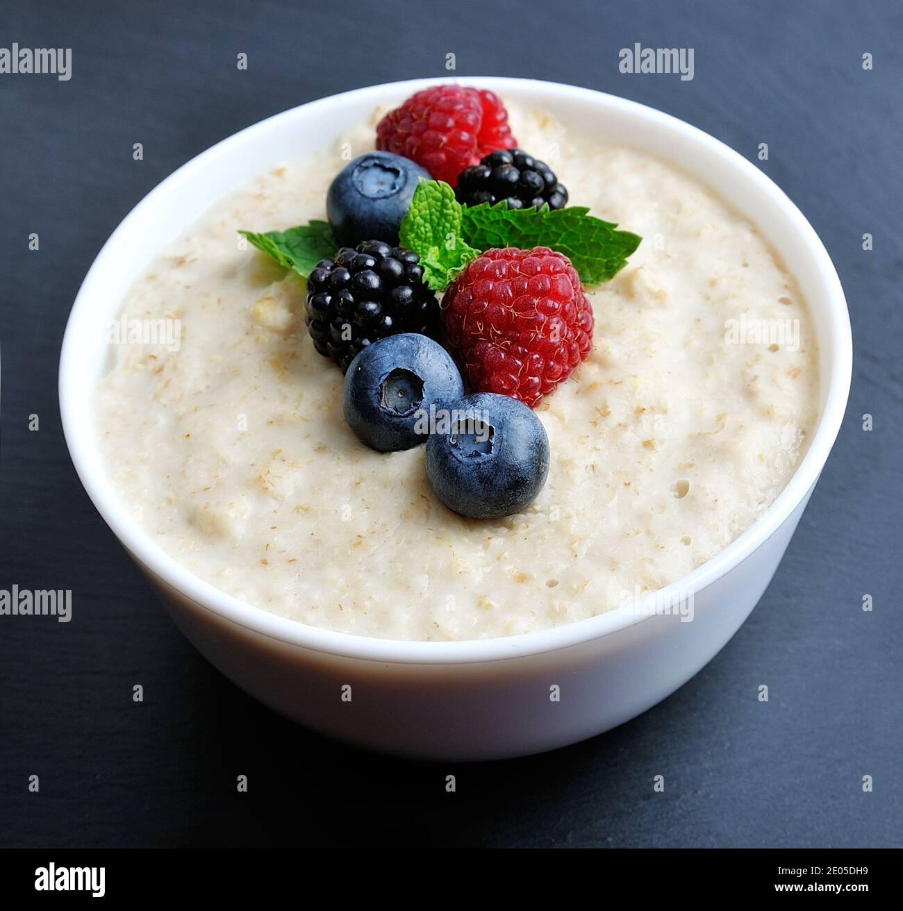 Healthy breakfast. Porridge bowl with berries on a black graphite background. Stock Photo