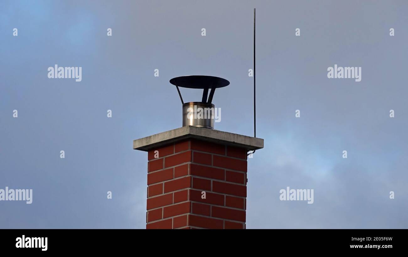 brick chimney and lightning conductor, blue sky, gray clouds Stock Photo