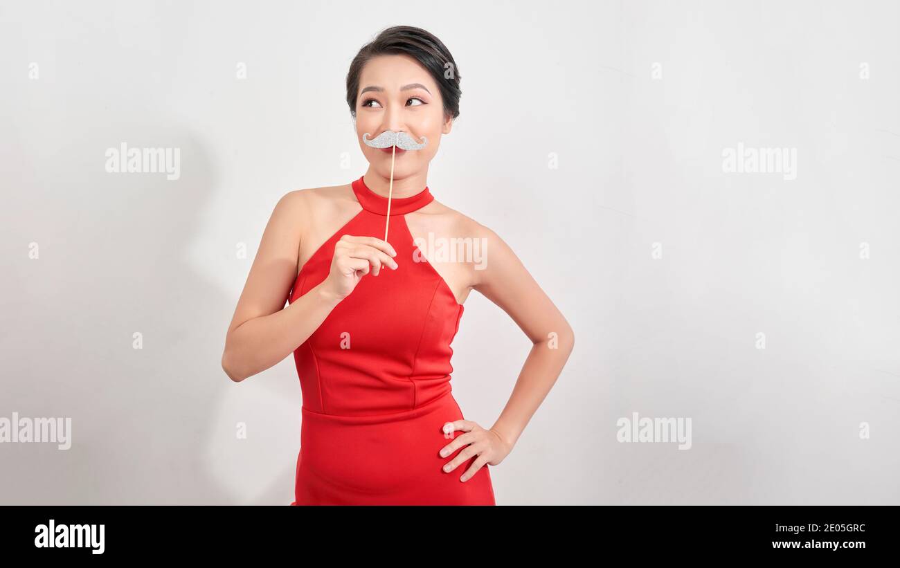 Portrait of trendy lady with beaming smile having carton paper cutout mustache on stick isolated on white background Stock Photo