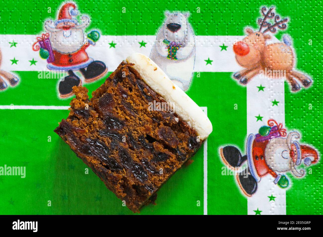 Slice of M&S Iced Fruit Cake Christmas Cake set on green Christmas serviette napkin - UK festive Xmas Stock Photo