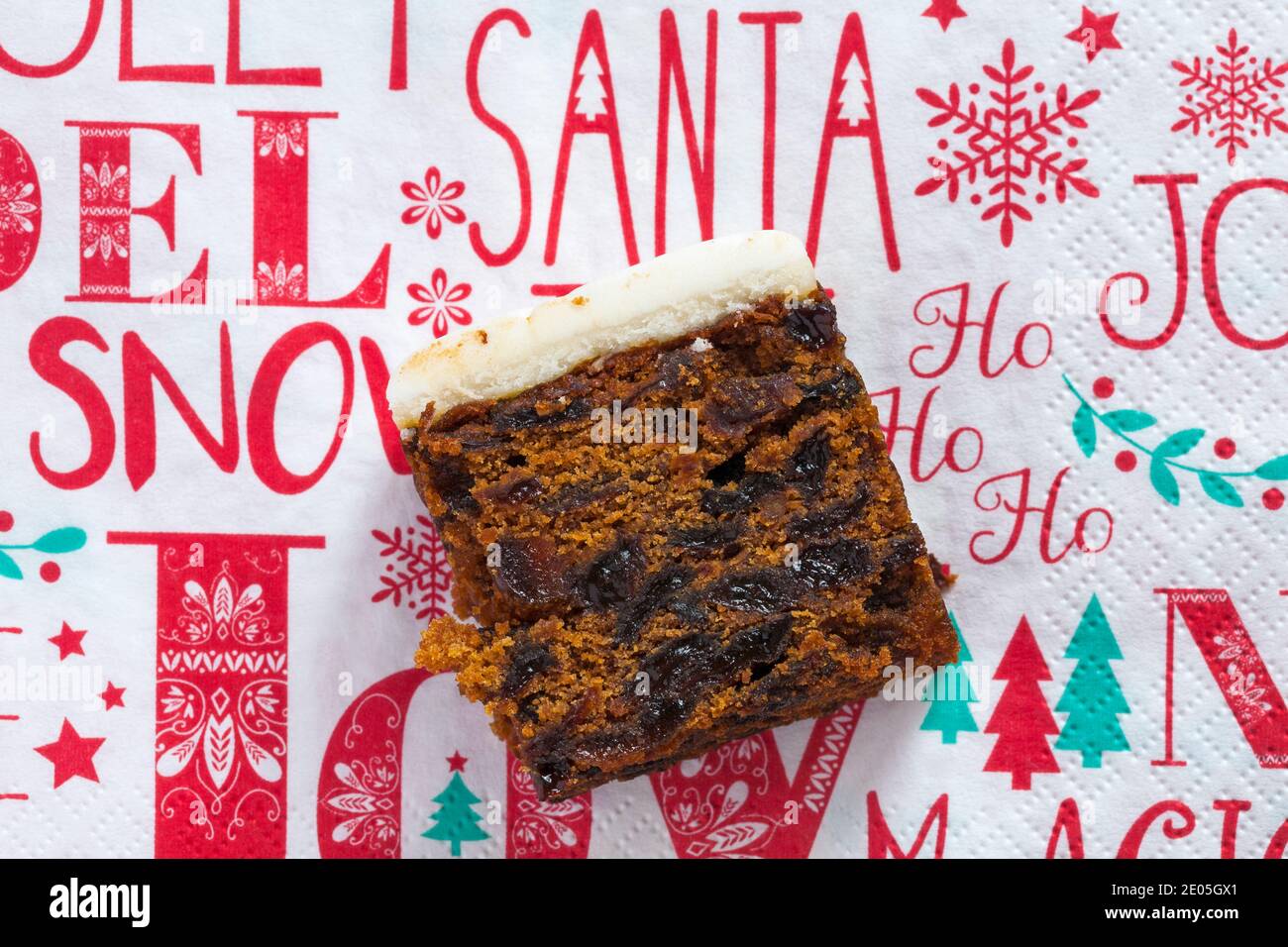 Slice of M&S Iced Fruit Cake Christmas Cake set on Christmas serviette napkin - UK festive Xmas Stock Photo
